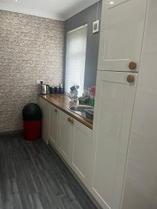 een keuken met witte kasten en een spoelbak bij Rowan in Bellshill