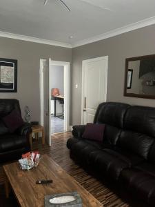 een woonkamer met een leren bank en een tafel bij Rowan in Bellshill