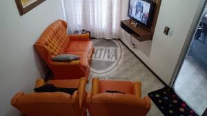 a living room with a couch and a tv at Triplex no Centro e Pertinho da Praia in Guaratuba