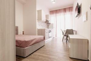 a bedroom with a bed and a table and a kitchen at Vicolo Mediterraneo Apartment in Reggio di Calabria