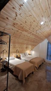 a room with three beds and a wooden ceiling at Guest house marissi in Surami
