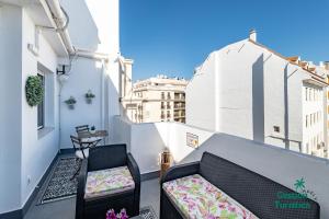a balcony with a couch and a chair on a building at Ático centro Huelva con parking in Huelva