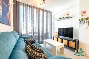 a living room with a blue couch and a tv at Ático centro Huelva con parking in Huelva