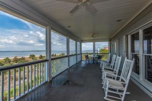 a porch with white chairs and a table and the ocean at The Pearl in Edisto Island
