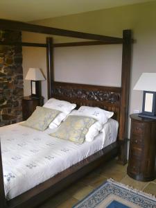 a bedroom with a large wooden bed with two pillows at Casona Asturiana Los Gamonales in Logrezana