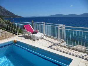 a swimming pool with a chair next to the water at Apartments and rooms with a swimming pool Brist, Makarska - 15620 in Brist