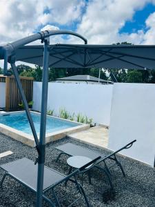 a chair and an umbrella next to a swimming pool at Oasis in Petit-Bourg
