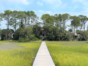 a wooden boardwalk through a field of tall grass at Marsa's Place in Edisto Island