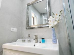 lavabo con espejo y jarrón de flores en Santelmo,16, en Málaga