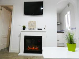 Una sala de estar con chimenea y un televisor en la pared. en Santelmo,16, en Málaga