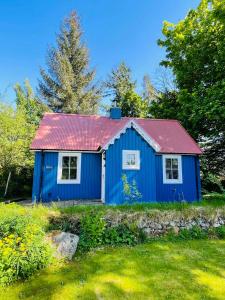 a blue house with a red roof in a yard at Ardshiel in Foyers