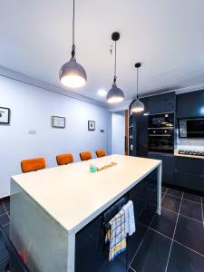 eine Küche mit einer weißen Theke und orangefarbenen Stühlen in der Unterkunft The Glisson Residence, Adenta in Santeo + 12 Fotos