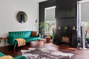 ein Wohnzimmer mit einer grünen Couch und einem Kamin in der Unterkunft Jungle House Chillicothe Sleeps 24 Downtown Ohio Free Parking - Walk to Historic District - 5BR Luxury Home - Pet Friendly - King Beds - Over 5,800 Five Star Stays in Chillicothe