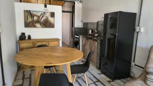 a kitchen with a wooden table and a black refrigerator at Espacio Inn zona Kempes in Córdoba