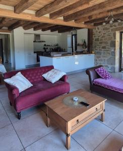 a living room with a purple couch and a coffee table at La rivière maison piscine emplacement idéal in Autoire