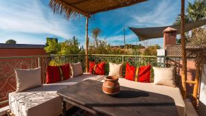 a porch with pillows and a table on a balcony at Riad Dar Tiflet in Marrakech
