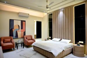 a bedroom with a bed and two chairs at FLORENTINO The Luxury Villa in Amritsar