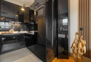 una cucina con mobili neri e una porta in vetro di Stylish apartment with balcony & lift a Parigi