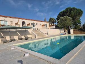 a swimming pool with chairs and umbrellas next to a building at Casa Tío, L'hacienda de Soubran, classé 4 étoiles in Soubran