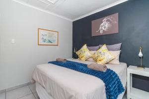 a bedroom with a bed with a blue accent wall at The Bridge, Apartment 67 in St Lucia +24 photos