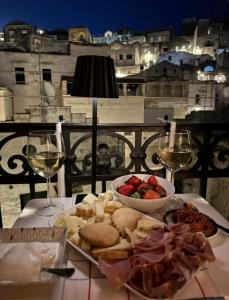 een tafel met een bord eten en glazen wijn bij Radici - La finestra sui Sassi in Matera