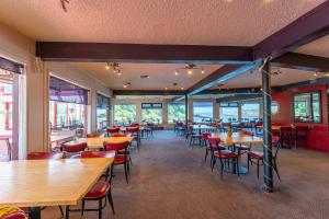 un restaurant avec des tables et des chaises en bois et des fenêtres dans l'établissement Anchor Lodge, à Fort Bragg