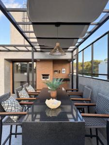 eine Terrasse mit einem Tisch, Stühlen und Fenstern in der Unterkunft Estudio Aurea Bauten 210 in Tambaú