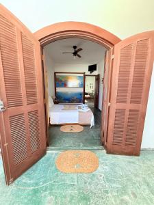 a bedroom with a bed and open doors at Pousada Vó Nina in Arraial do Cabo