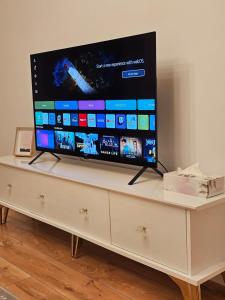 a flat screen tv sitting on top of a white dresser at White Central Apartment in Bistriţa +4 photos