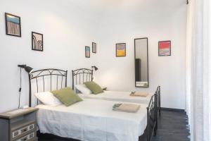 Dos camas en una habitación con paredes blancas y espejos. en Il Cantuccio di Vittorio - Apartment with private garden in the Heart of Volterra, en Volterra 15 fotos más