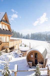 a wooden cabin in the snow with a deck at Ostoja Spokoju in Kościelisko