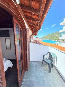 a balcony with a chair and a view of the ocean at Pousada Vó Nina in Arraial do Cabo