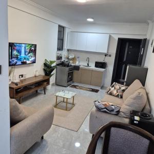 a living room with a couch and a kitchen at Golden Mango Heights - Urban Family Suite - One Bedroom Apartment - Restaurant, Workspace, City Views, Fast WiFi, Sauna, Fitness Facilities, Secure Parking And Kids Play Area in Nairobi +15 photos