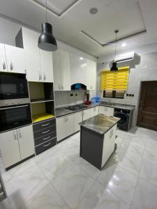 una gran cocina con armarios blancos y una isla negra en Beautiful peaceful comfortable, en Lekki