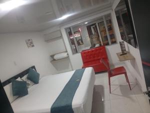 Habitación con cama y silla roja en hotel bogota corferias, en Bogotá