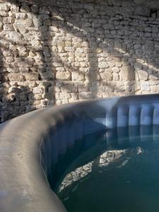 une piscine d'eau à côté d'un mur de briques dans l'établissement Les maisons des Frangines, à Oinville-Saint-Liphard