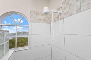 Un baño blanco con ventana y ducha. en Oceanview • Mins to the Beach • Private BR Balcony, en Moule à Chique 7 fotos más