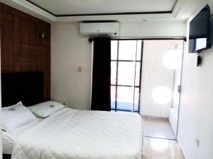 a bedroom with a white bed and a window at Hotel Adulam in Santa Cruz de la Sierra +1 photo