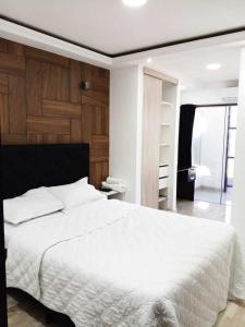 a bedroom with a white bed and a wooden wall at Hotel Adulam in Santa Cruz de la Sierra