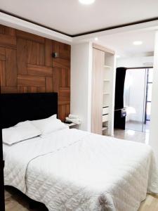 a bedroom with a white bed and a wooden wall at Hotel Adulam in Santa Cruz de la Sierra