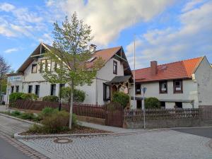 a white house with a tree in front of a fence at Ferienhaus „Schlupfwinkel“, kostenloser Parkplatz, Vollausstattung in Ilmenau