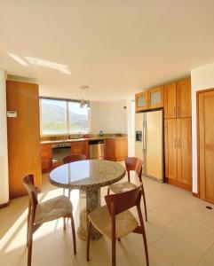 a kitchen with a table and chairs and a refrigerator at PENTHOUSE EN PLAYA EL AGUA in Los Cerritos