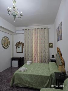 Un dormitorio con una cama verde y una lámpara de araña. en B&B Domus Morfeo, en Santa Maria Capua Vetere