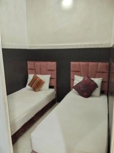 - 2 lits dans une chambre de couleur blanche et rose dans l'établissement DAR IJLAL, à Marrakech