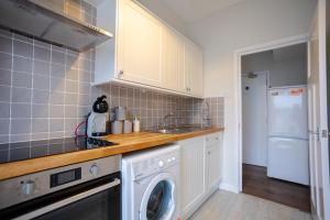 eine Küche mit Waschmaschine und Waschmaschine in der Unterkunft Modern 2 BR Apt with Free parking in Cardiff Pontcanna in Cardiff + 24 Fotos