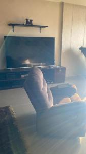 a living room with a large television and a chair at شقة مفروشة سوبر لوكس علي النيل in Mansoura +3 photos