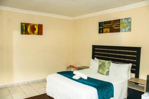 a bedroom with a bed and two paintings on the wall at Stopover lodge in Rustenburg