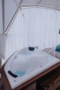 a large bath tub in a room with a bed at Enxe Glamping & Spa 