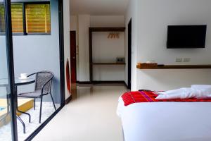 a bedroom with a bed and a table and a tv at The Umbrella House - SHA Extra Plus in Kamala Beach