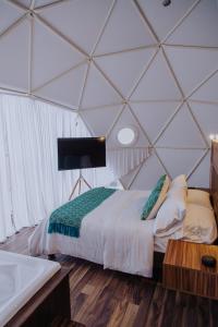 a bedroom with a bed and a tub in a tent at Enxe Glamping & Spa 